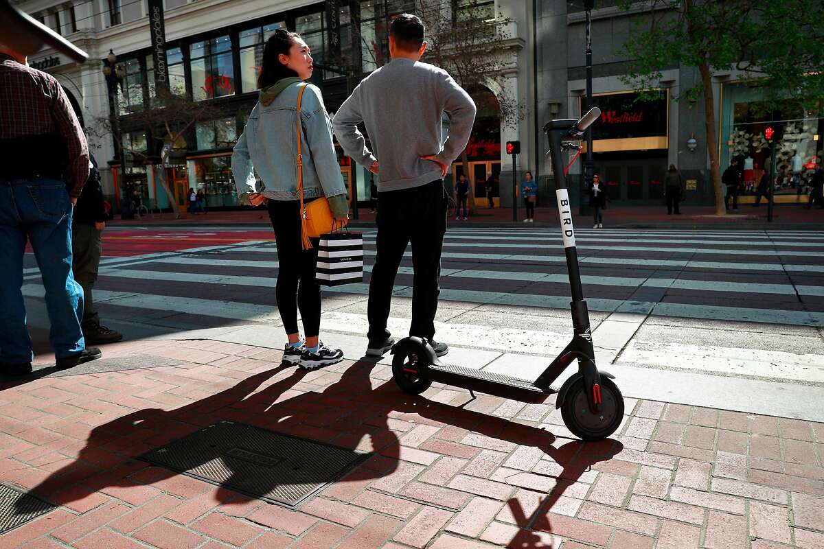 A Bird scooter parked along Market St. as pedestrians wait at the crosswalk as seen on Mon. April 9, 2018, in San Francisco.