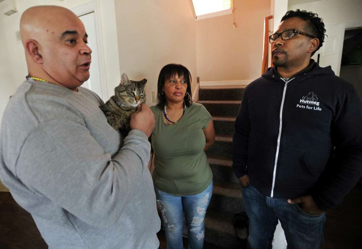 Christopher Keith, right, community outreach manager for the Humane Society's Pets for Life program, meets with Chico Gavillan and Millie Navarro and Rocky, one of the former stray cats they've adopted in their home on Shelton Street in Bridgeport, Conn. on Tuesday, March 27, 2018. Pets for Life provides free spay and neutering services through community outreach in specific zipcodes.