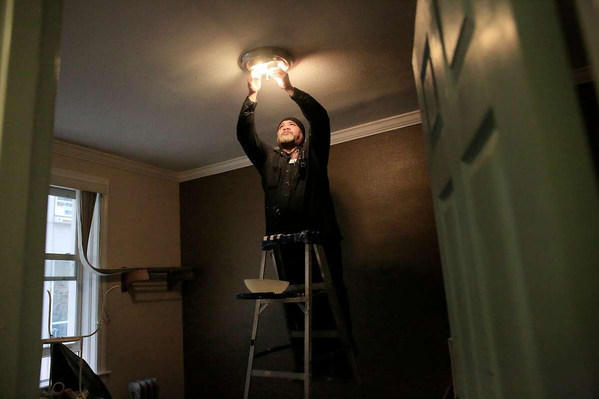 Tito Solifona, maintenance technician, replaces old bulbs with new LED bulbs in a vacant unit at a community housing development run by Swords to Plowshares on Tuesday, April 10, 2018, in San Francisco, Calif. San Francisco's Department of the Environment is providing 100,000 free LED lightbulbs to city residents, particularly disadvantaged ones under a new program.