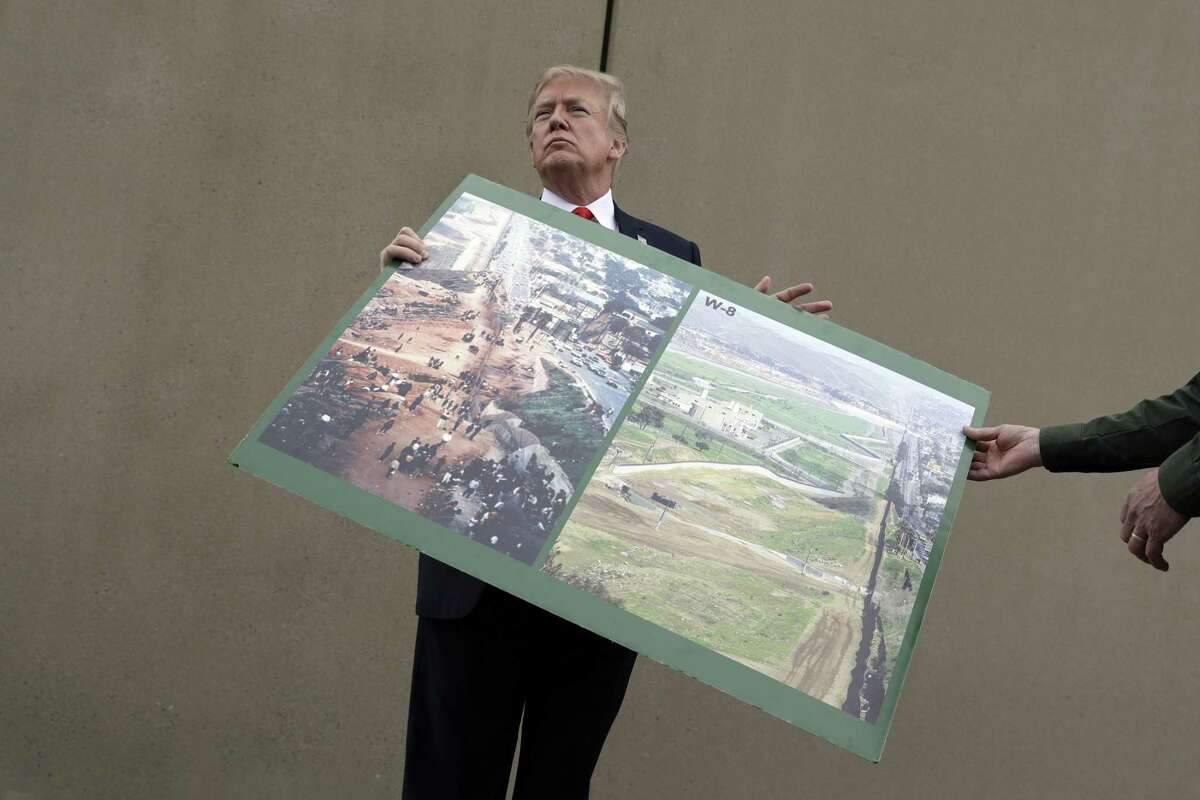 President Trump holds a photo of the border area as he reviews border wall prototypes during a visit to San Diego in March. A reader says the proposed wall would do more than keep people out.
