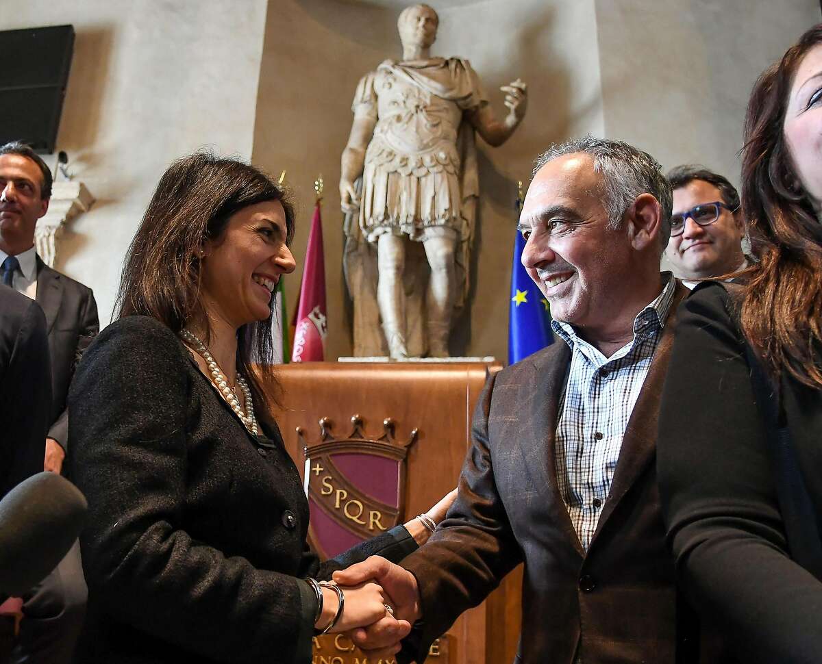 Roma president James Pallotta, right, shakes hands with Rome Mayor Virginia Raggi during a meeting in Rome, Wednesday, April 11, 2018. James Pallotta has agreed to pay a fine and has apologized to Mayor Virginia Raggi for jumping into a downtown fountain to celebrate the win over Barcelona. Pallotta was ecstatic after Roma surprised Barcelona with a 3-0 win Tuesday to overturn a three-goal first-leg deficit in the Champions League quarterfinals. (Alessandro Di Meo/ANSA via AP)