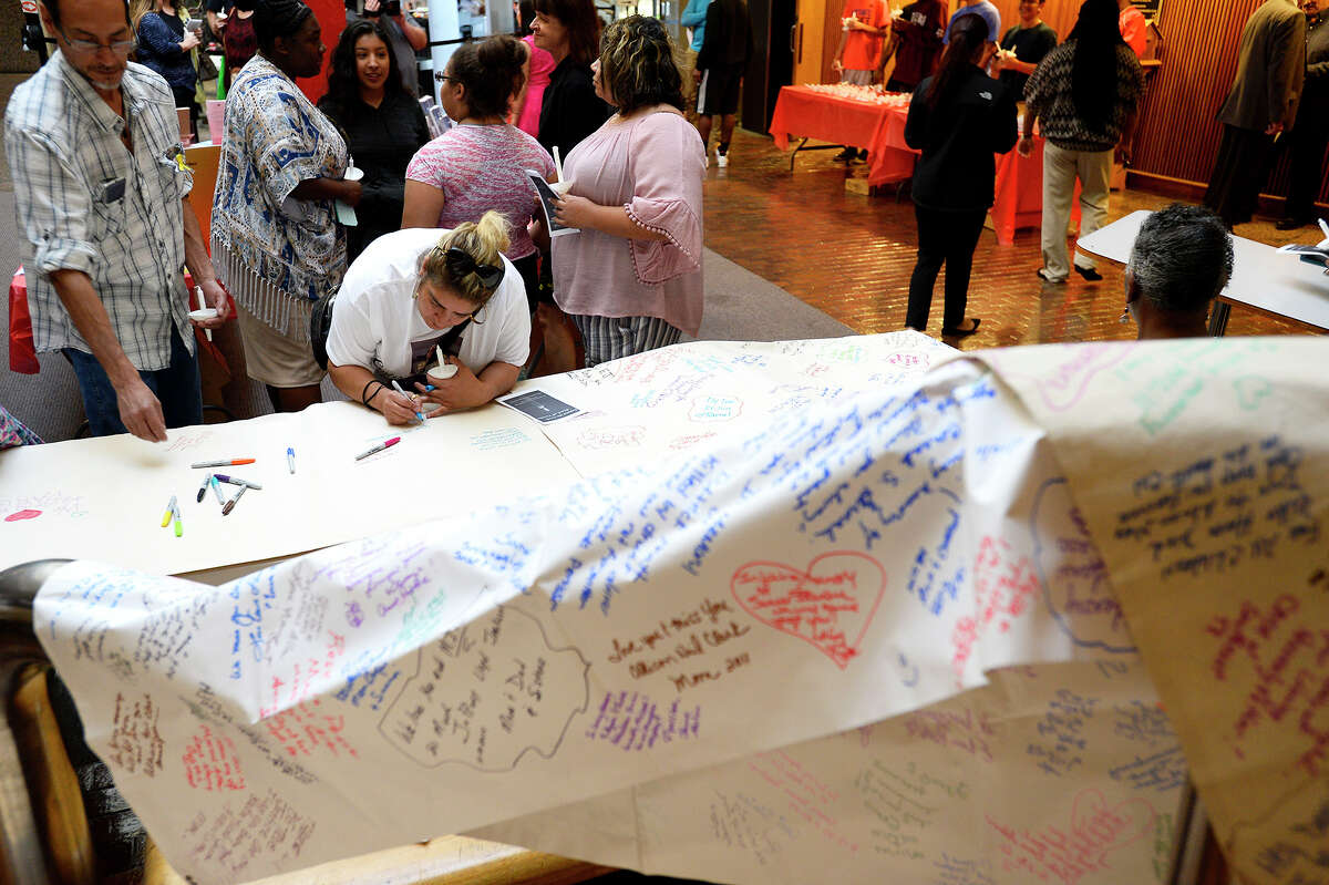 Attendees write messages on a banner at the 28th Annual Crime Victim's Candlelight Vigil at the Jefferson County Courthouse. The vigil was held to remember crime victims as part of National Crime Victims' Rights Week. Photo taken Thursday 4/12/18 Ryan Pelham/The Enterprise