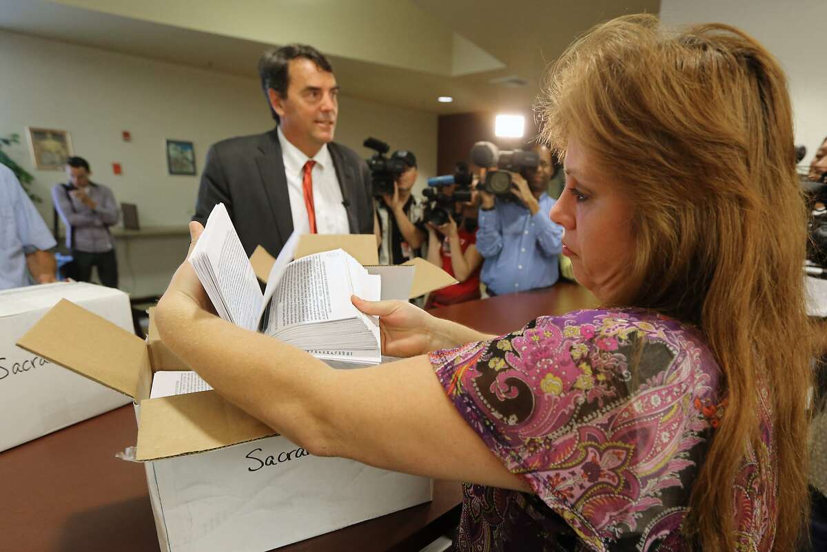 Heather Ditty, elections manager for the Sacramento County Registrar of Voters, makes a quick inspection of some of the petitions turned in by Silicon Valley venture capitalist Tim Draper, left, that would place a ballot initiative before voters asking to split California into six separate states, Tuesday, July 15, 2014, in Sacramento, Calif. Draper delivered what he said were 44,000 signatures, of the 1.3 million the Six California's campaign plans to submit statewide this week. If enough signatures are verified, voters in November 2016 would be asked to divide the state into six states called Jefferson, North California, Silicon Valley, Central California, West California and South California. (AP Photo/Rich Pedroncelli)