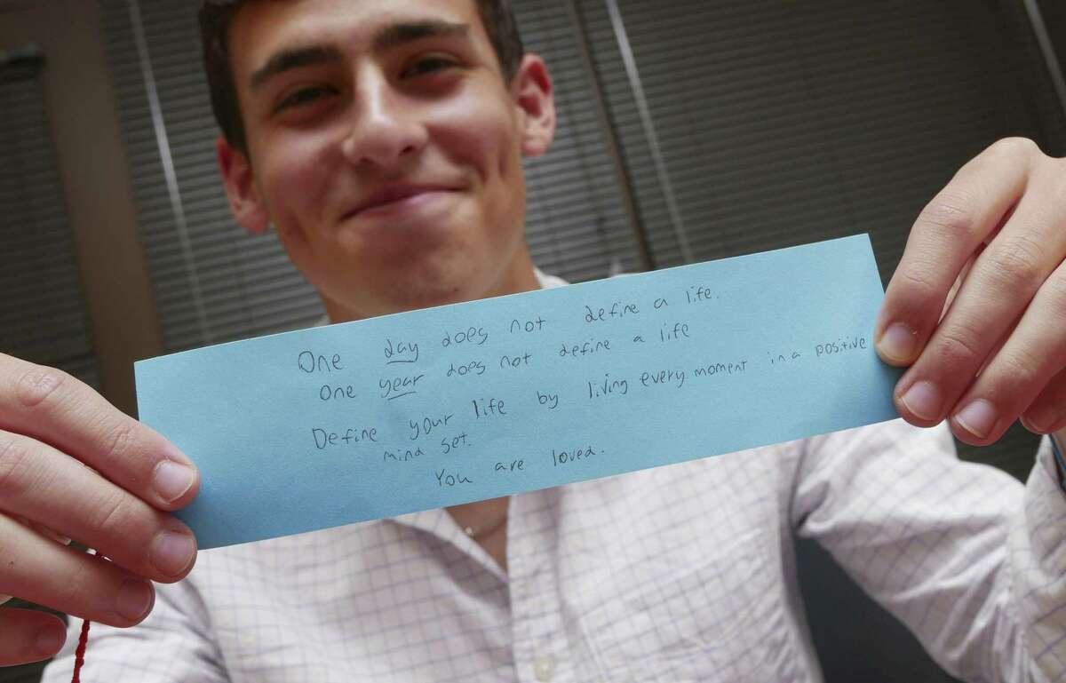 Churchill High School student Jordan Wolf displays a note that he wrote to go with a bracelet that he weaved in the Threads of Love program. The message is meant to encourage a fellow student who may need some support.