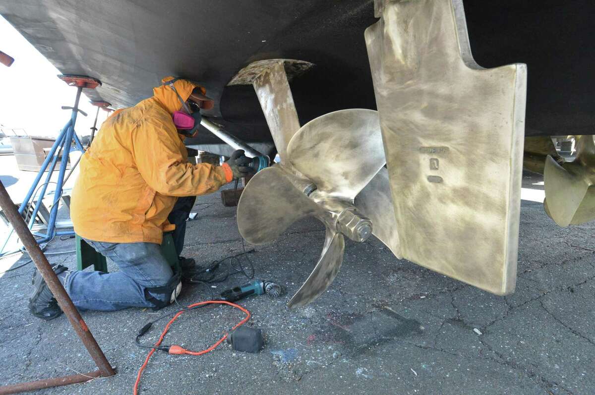 Norm Allen from Fairfield uses a wire polishing wheel to clean the drive shaft, propeller and rudder of barnacles and rust on his 52ft pleasure boat at Cove Marina on Sunday April 8, 2018 in Norwalk.