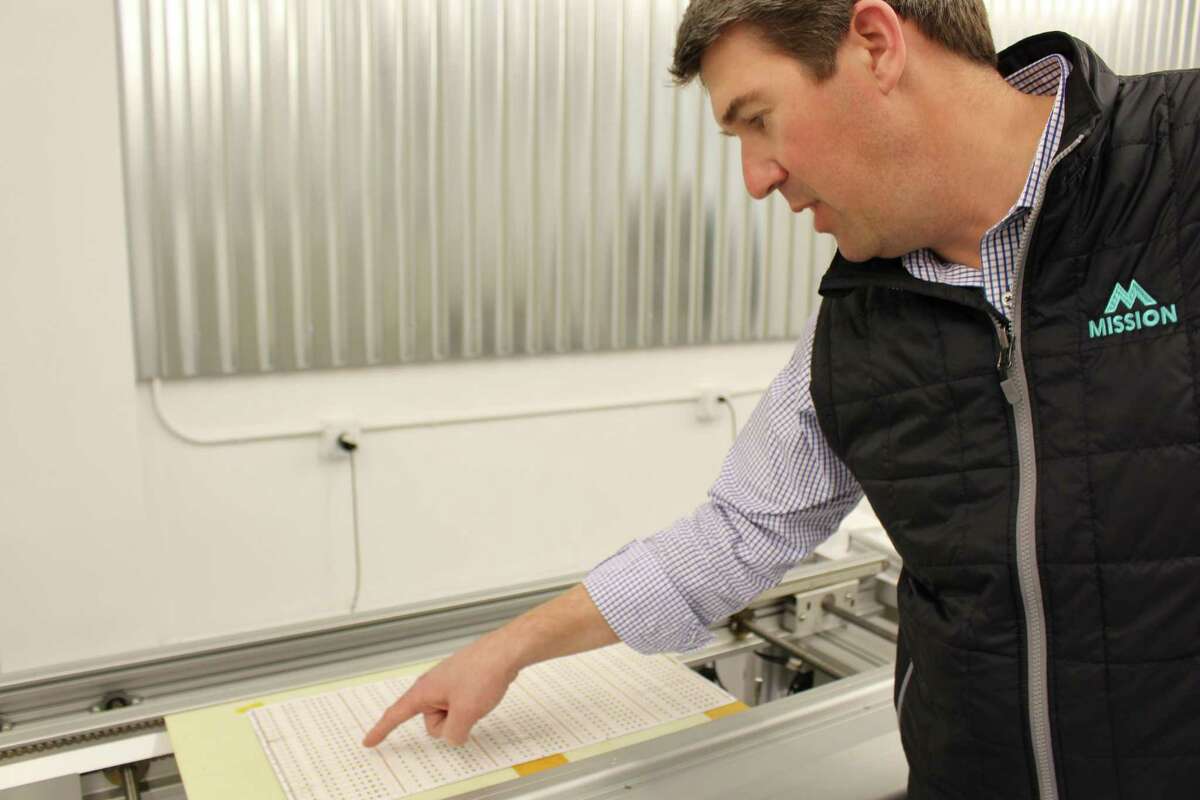 Gean Tremaine, president of Q-Tran, Inc. inspects newly mounted LED lights in the Milford-based company’s new expansion.