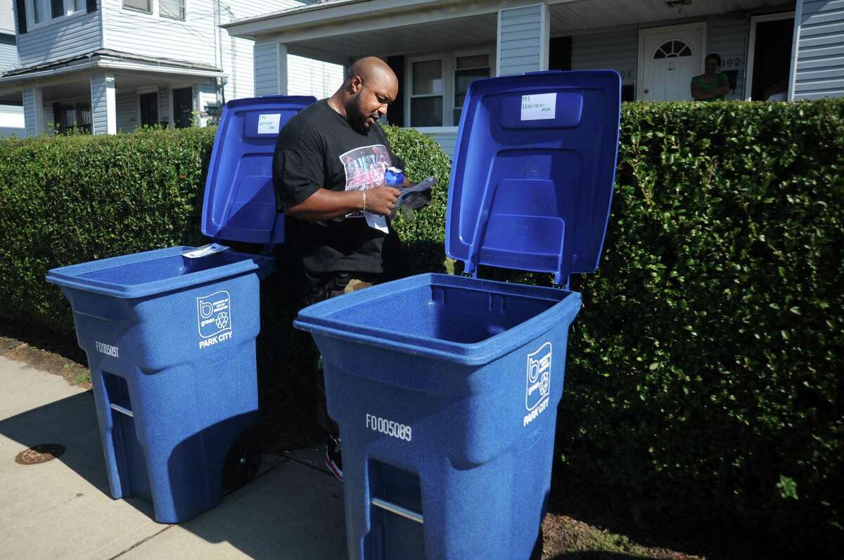 Rayshawn Smith reads the pamphlet he received with a new blue Toter bin. In Torrington, Mayor Elinor Carbone is seeking ways to encourage residents to properly dispose of their waste, allowing the city to earn points and funding. The city uses Toters for recycling and regular trash bins for garbage.
