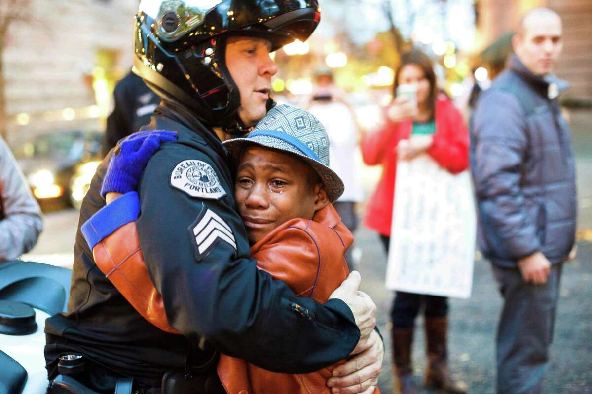 FILE - In this Nov. 25, 2014, file photo provided by Johnny Nguyen, Portland police Sgt. Bret Barnum, left, and Devonte Hart, 12, hug at a rally in Portland, Ore., where people had gathered in support of the protests in Ferguson, Mo. The SUV carrying the Hart family, from Woodland, Wash., that plunged off a coastal cliff near Mendocino, Calif., recently, killing all passengers, accelerated straight off the cliff and authorities said the deadly wreck may have been intentional. (Johnny Huu Nguyen via AP, File)