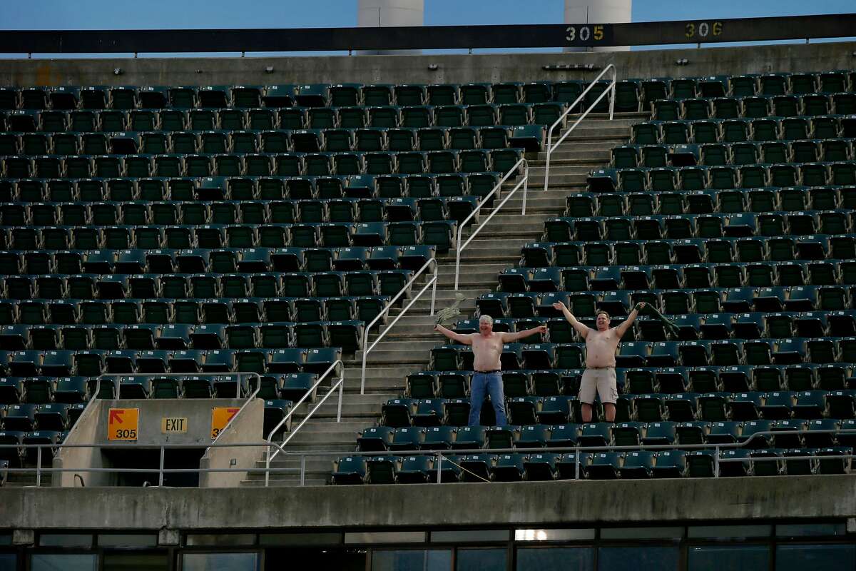 Oakland Athletics fans take their shirts off as they're broadcasted in the coliseum before an MLB game between the Athletics and Los Angeles Angels at the Oakland Coliseum, Friday, March 30, 2018, in Oakland, Calif.