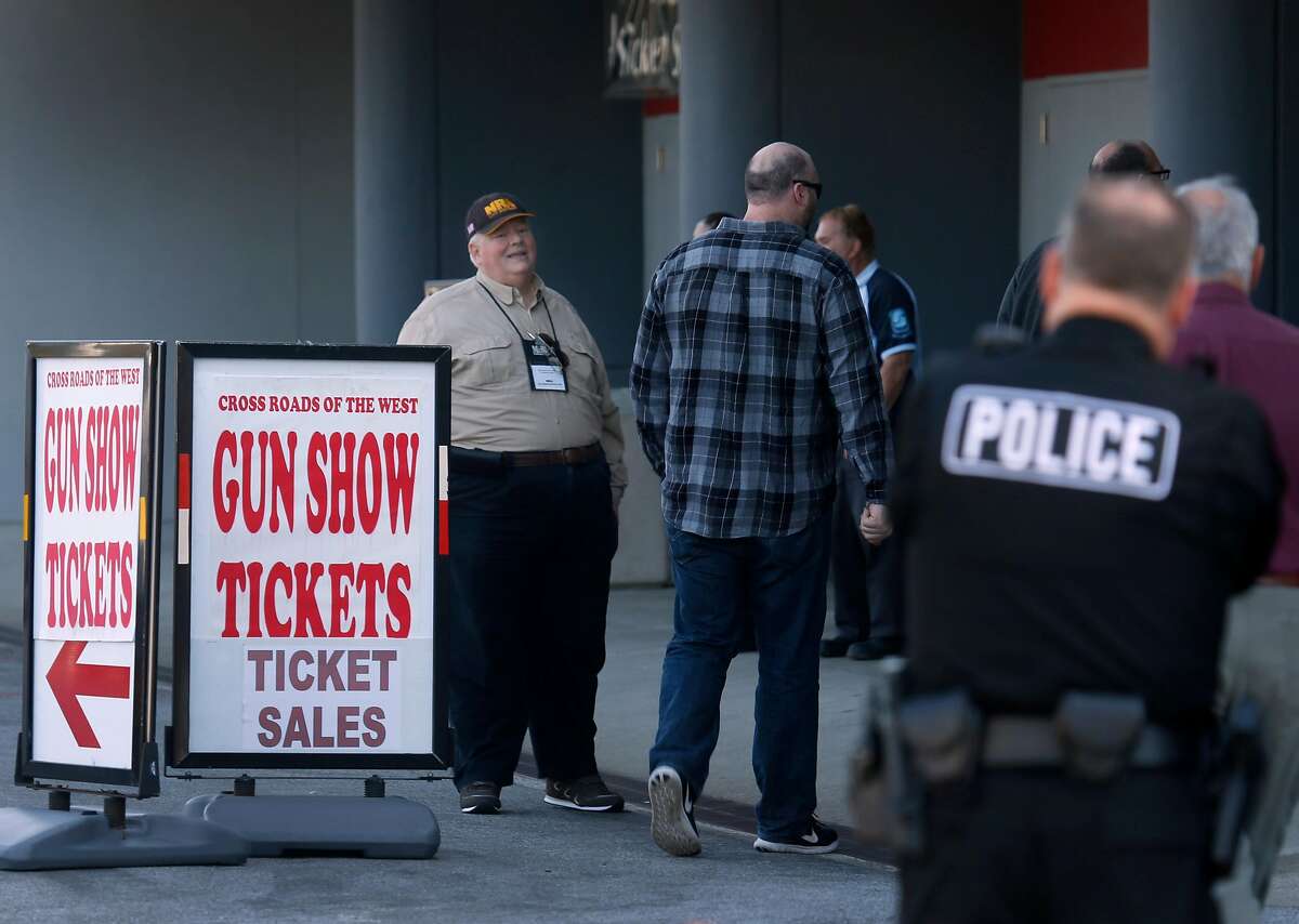 At left, a man representing the National Rifle Association offers free admission to the Crossroads of the West gun show for attendees who join the NRA or renew their membership at the Cow Palace in Daly City, Calif. on Saturday, April 14, 2018.