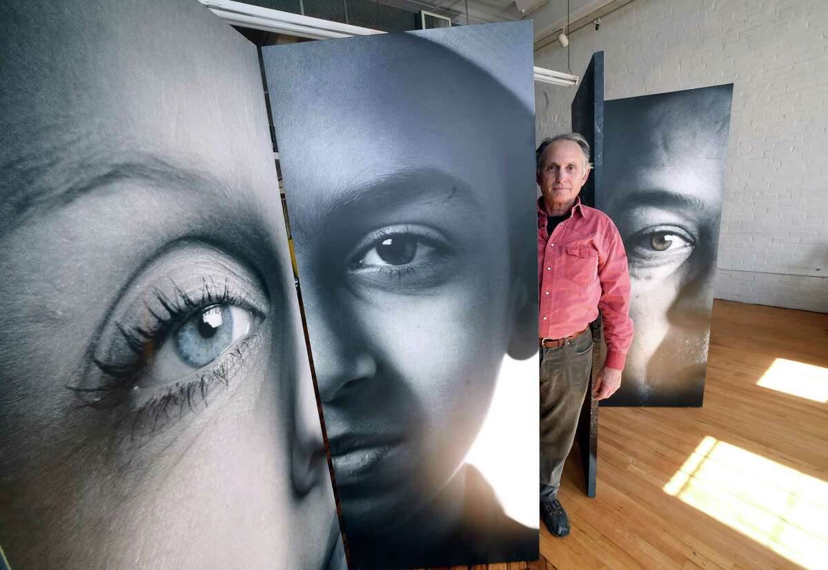 Joe Standart of Lyme is photographed with portraits of immigrants that were part of the New London show, We Are a Nation of Immigrants, at the Urban Collective in New Haven on March 23, 2018.