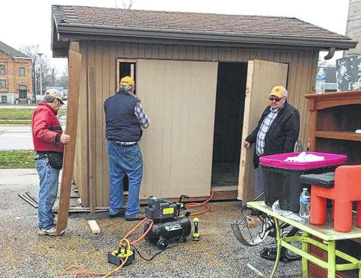 Lions Club members Ron Price, Tom Atkins and Larry Whewell work to replace the door on a storage shed at New Directions Warming and Cooling Center.