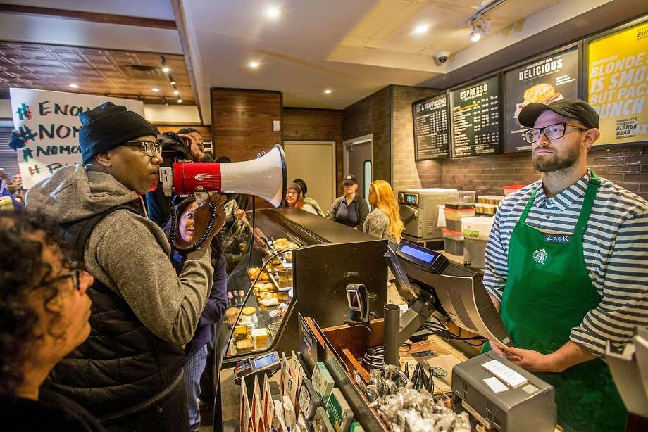 Local Black Lives Matter activist Asa Khalif, left, stands inside the Starbucks at 18th and Spruce, and over a bullhorn, demands the firing of the manager that called police, which resulted in two black men being arrested. On Sunday April 15, 2018, protesters demonstrated outside the Starbucks and planned to return Monday. (Michael Bryant//Philadelphia Inquirer/TNS) Photo: JESSICA GRIFFIN, TNS