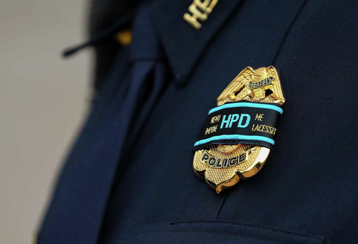 Houston police officers wear a band that roughly translates to "No one provokes me with impunity" during a recent funeral for an officer.