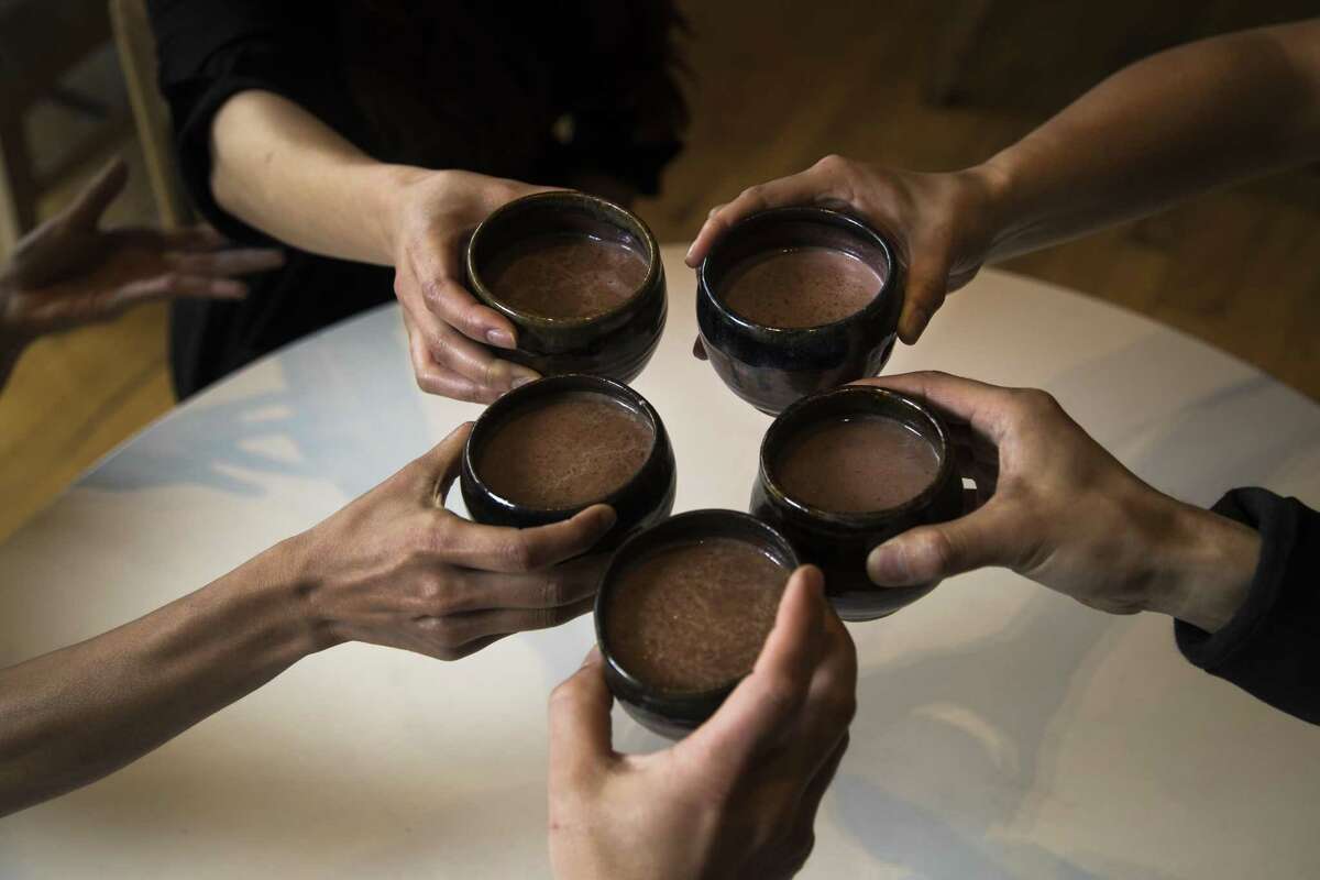 A group of Xochi restaurant guests raise their cups of Oaxacan hot chocolate that was prepared tableside.