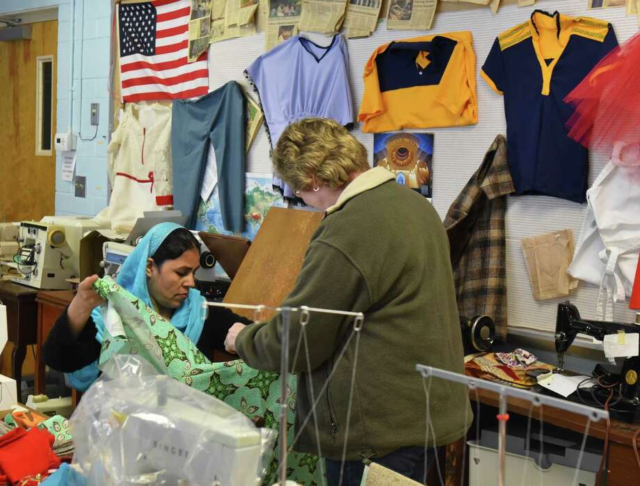 Fatima, a refugee from Afghanistan, shows a traditional dress she's sewing to Judith Smith, executive director of the Literacy Volunteers of Rensselaer County, at a sewing class in Rensselaer's McManus Center on April 14, 2018. The class, sponsored by the Literacy Volunteers of Rensselaer County, takes place every Saturday to help refugees practice their sewing and English skills. (Massarah Mikati/Times Union)
