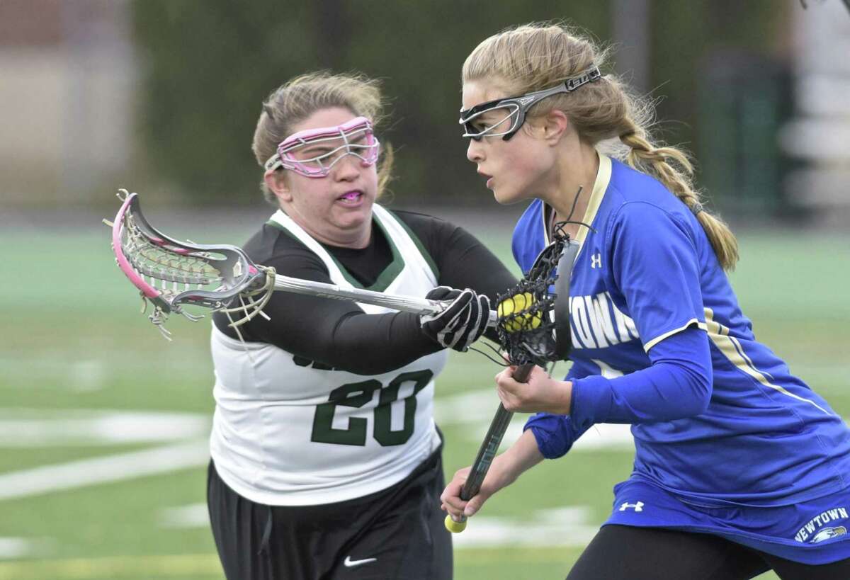 New Milford’s Hannah Clark (20) defends Newtown’s Lindsey Merrifield during their girls lacrosse game Tuesday at New Milford High School.
