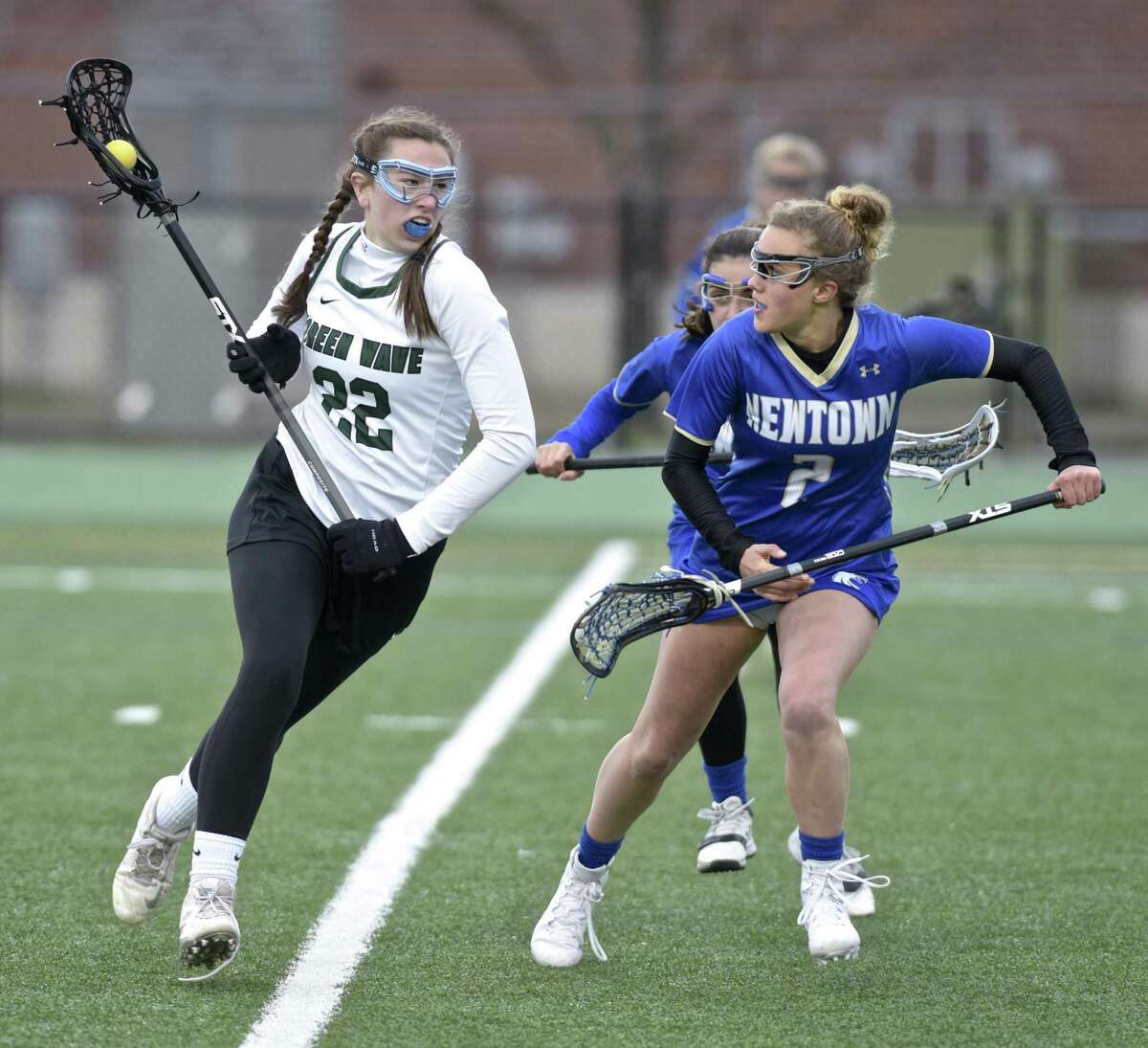 New Milford's Olivia Taub (22) moves the ball up field against Newtown's Cassidy Kortze (2) and Dylin Marano (44) in the girls lacrosse game between Newtown and New Milford high schools, Tuesday, April 17, 2018, at New Milford High School, New Milford, Conn.