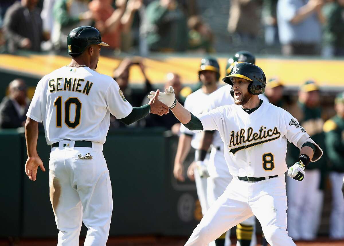 OAKLAND, CA - APRIL 18: Jed Lowrie #8 of the Oakland Athletics is congratulated by Marcus Semien #10 after he hit a two-run home run to give the Athletics a 11-10 lead in the eighth inning against the Chicago White Sox at Oakland Alameda Coliseum on April 18, 2018 in Oakland, California. (Photo by Ezra Shaw/Getty Images)