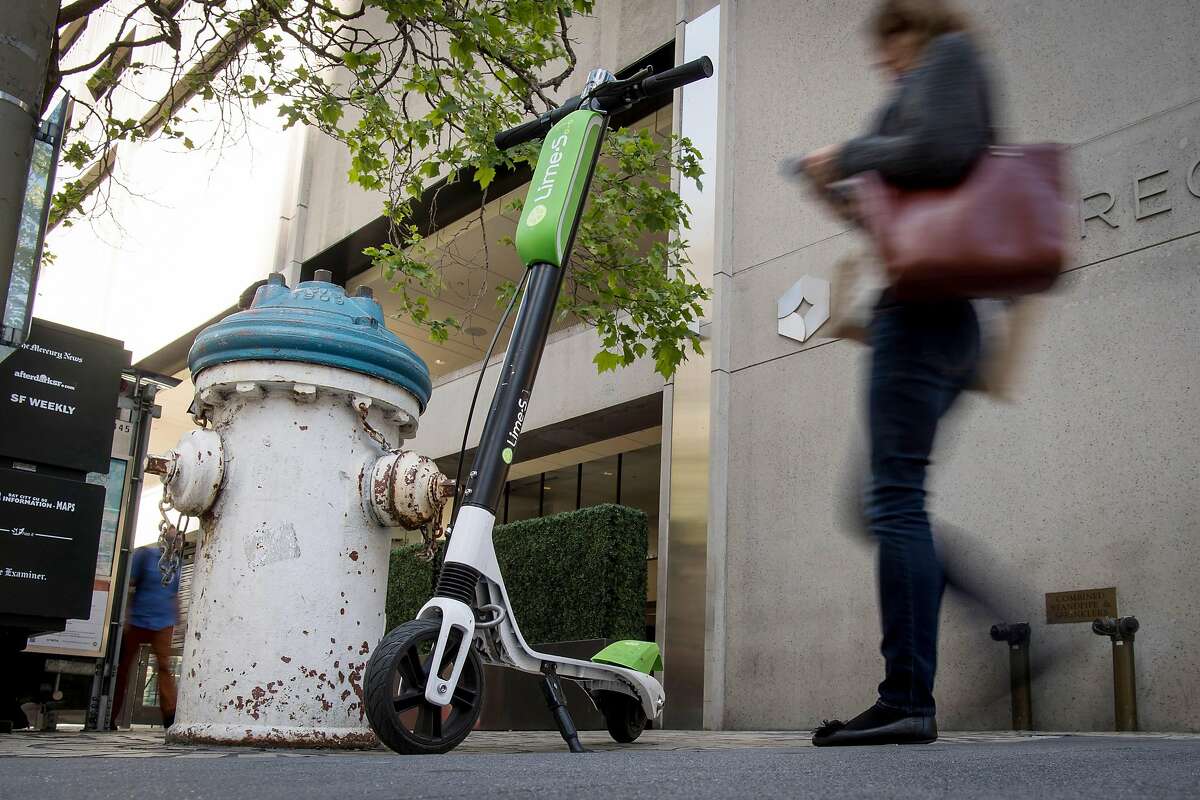 A pedestrian walks past a Neutron Holdings Inc. LimeBike shared electric scooter in San Francisco, California, U.S., on Friday, April 13, 2018. GPS-enabled�scooters�and bicycles are spreading across several major U.S. cities, driven by a wave of venture capital into a handful of companies.�Policymakers are scrambling to find ways to regulate the�great scooter boom of 2018. Photographer: David Paul Morris/Bloomberg