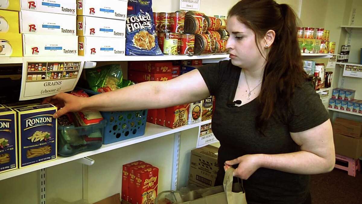 In this April 10, 2018 frame grab from video, student Hannah Daignault fills a grocery bag at the Schenectady County Community College food pantry in Schenectady, N.Y. As a 22-year-old student living on her own, Daignault finds it hard to stretch her student loans to cover the rising cost of books and fees, let alone food and rent, so she was thrilled when a campus food pantry opened last year. New York is the nation's first state to require free food pantries on all its public college campuses.