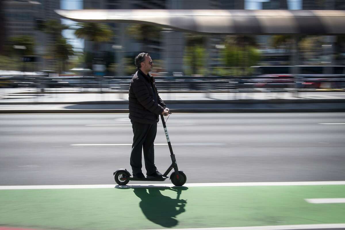 A person rides a Bird Rides Inc. shared electric scooter on the Embarcadero in San Francisco, California, U.S., on Friday, April 13, 2018. GPS-enabled�scooters�and bicycles are spreading across several major U.S. cities, driven by a wave of venture capital into a handful of companies.�Policymakers are scrambling to find ways to regulate the�great scooter boom of 2018. Photographer: David Paul Morris/Bloomberg