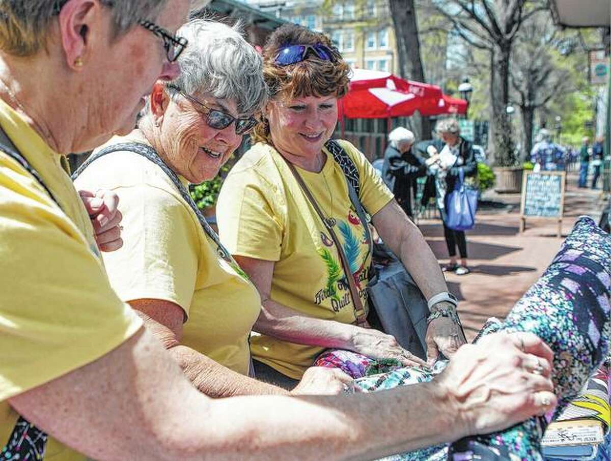 Deb Stagno (from left), Jane Laureys and Deb Malito, all of northern Illinois, inspect pieces of fabric for sale outside of Stane Lee in Paducah, Kentucky. Paducah turns into Quilt City USA in April as enthusiasts from around the world celebrate the art of quilting.