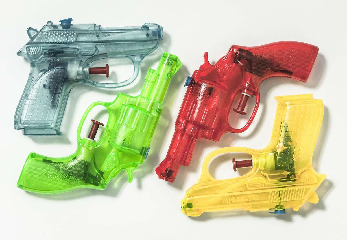 A group of colouful plastic water pistol are neatly arranged on a background