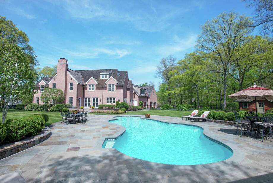 The in-ground swimming pool is surrounded by a bluestone patio. Closer to the house there is another bluestone patio with red brick sitting walls.
