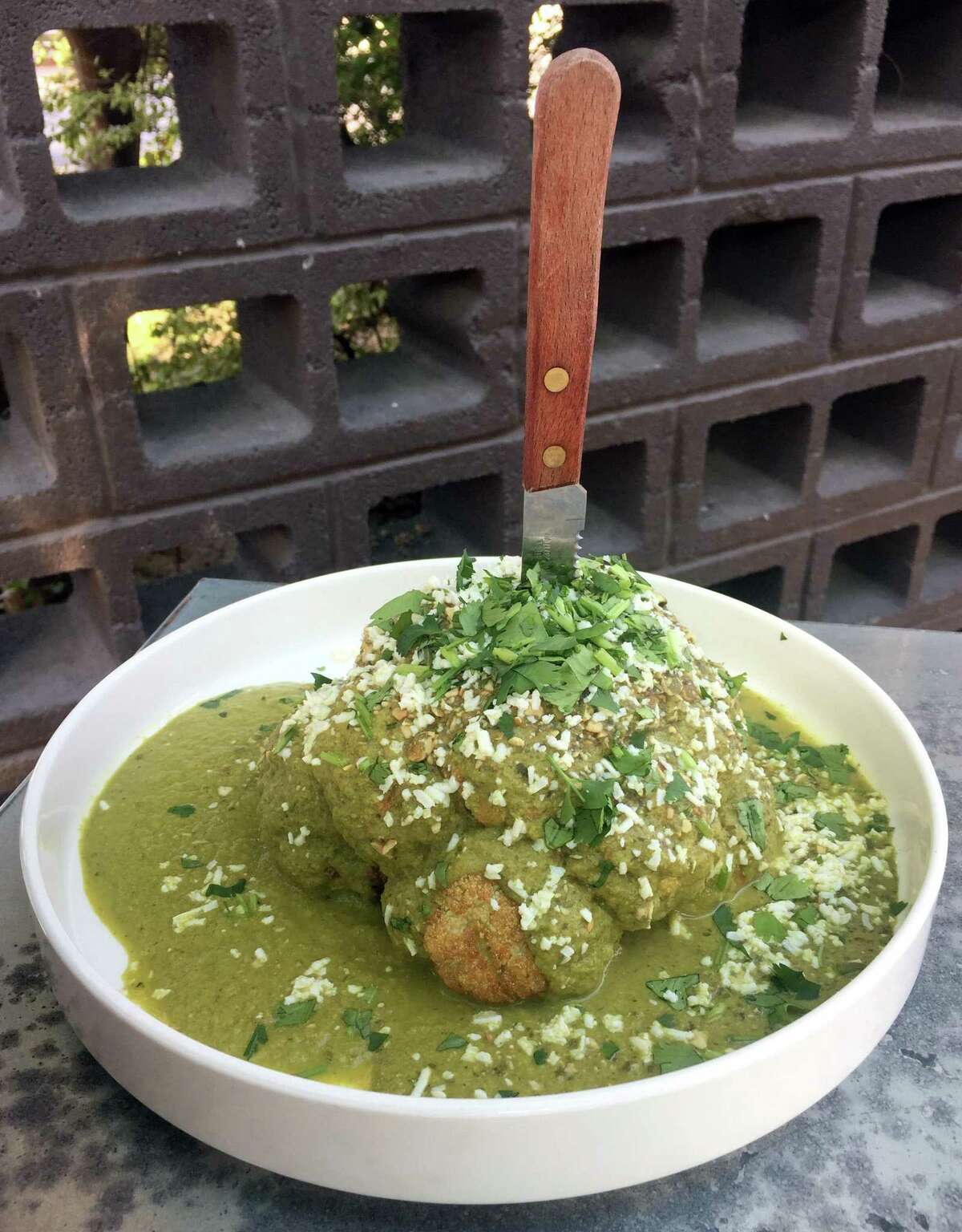 The Roasted Green Goddess Cauliflower at Chisme is served with green pipián mole, toasted green pumpkin seeds, Cotija cheese and cilantro.