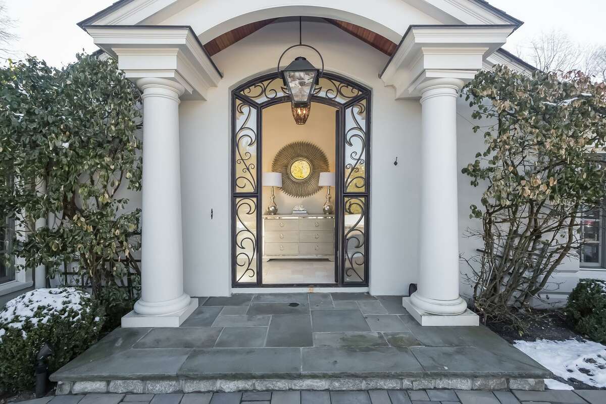 The front entrance features a custom hand-forged decorative iron and glass front door with a Charleston gas light above it.