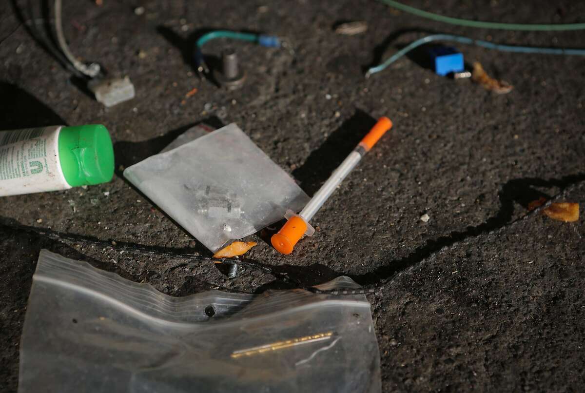 A hypodermic needle is seen on the sidewalk at a homeless encampment during a San Francisco Public Works Department cleaning at 8th and Brannan Streets in San Francisco, California, on Wednesday, July 1, 2015. The Department's "alley crew" visits homeless encampments on a daily basis to disinfect the ground and haul away refuse.