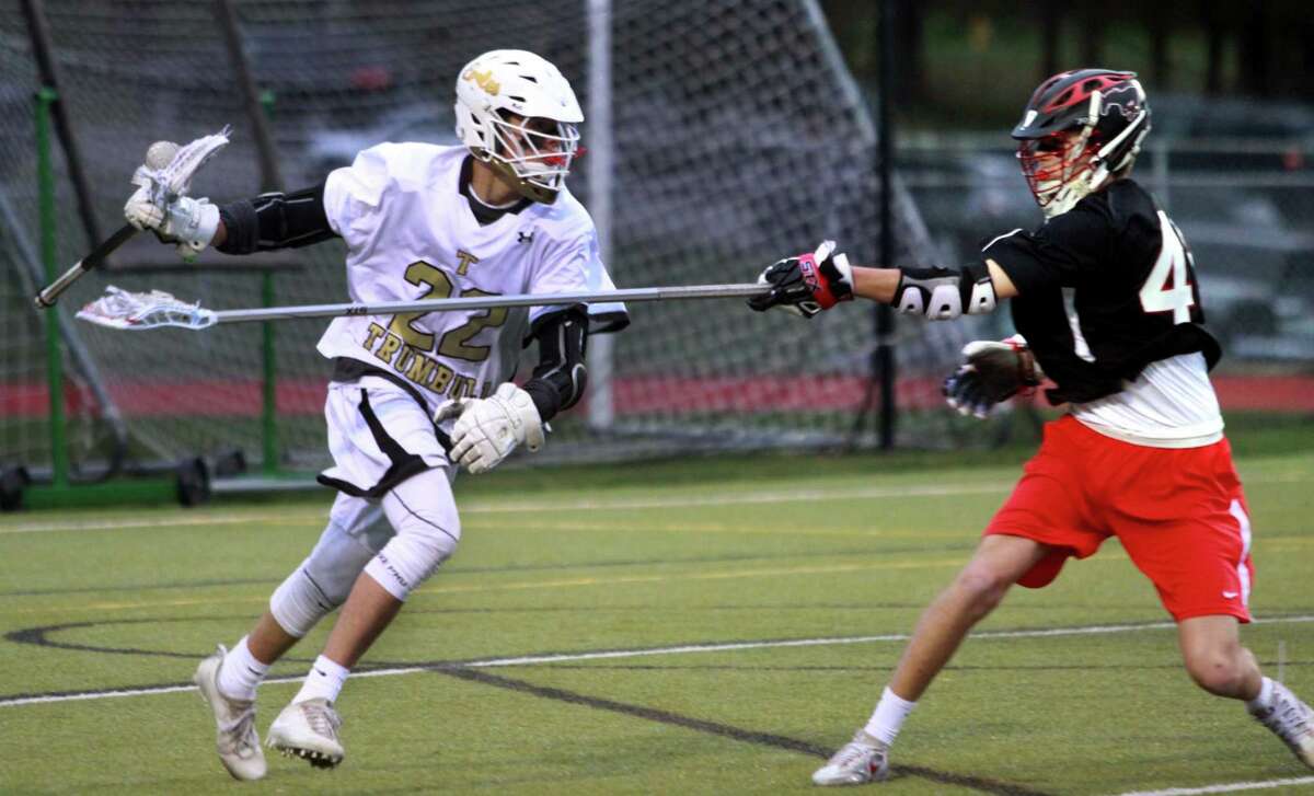 Trumbull's James O'Brien (22), left, comes from behind the goal as Fairfield Warde's Cole Hessell (45) defends during boys lacrosse action in Trumbull, Conn., on Tuesday Apr. 24, 2018.