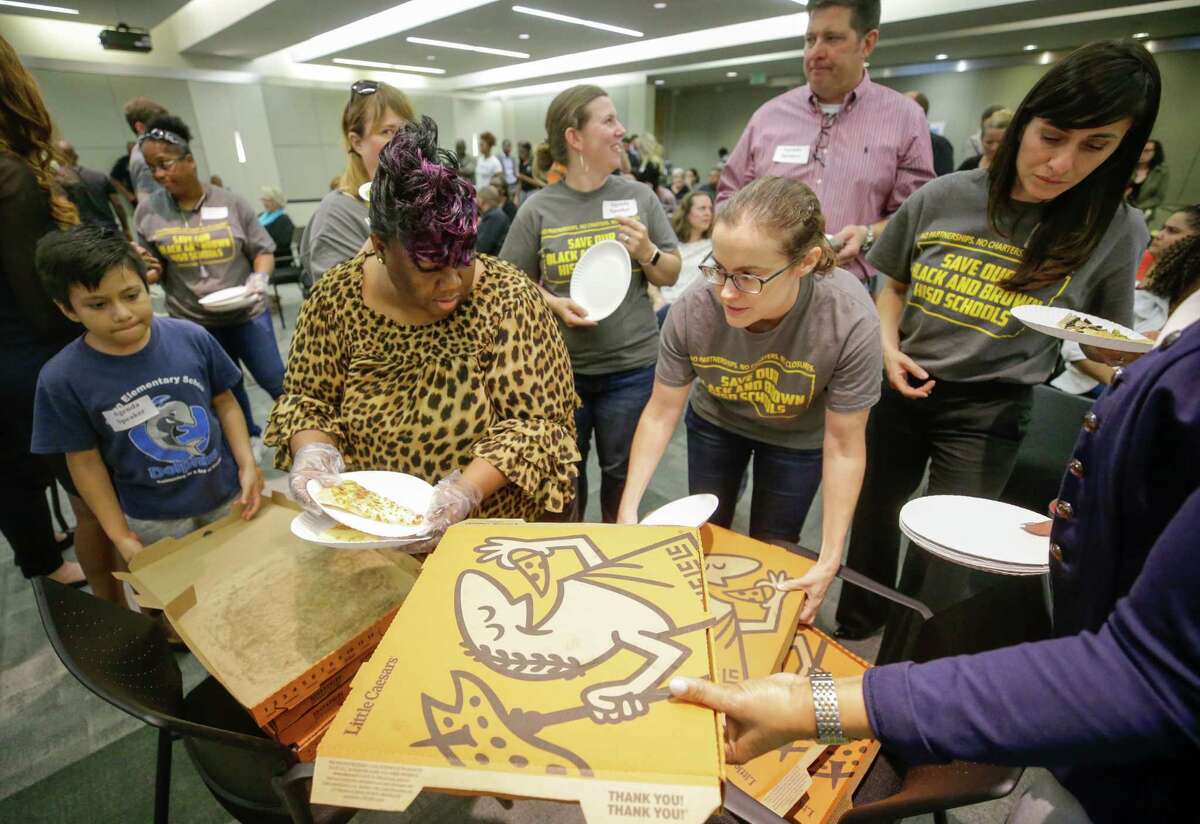 Erika Albert, left, dishes out pizza with others to a crowd who were waiting while the Houston ISD board were in a closed executive session Tuesday, April 24, 2018. Several people in the crowd bought the pizzas. The trustees were scheduled to vote on whether to hand over control of 10 chronically low-performing schools to Energized For STEM Academy, which already runs four in-district HISD charters. Many of the large crowd attending the meeting are against the partnership.