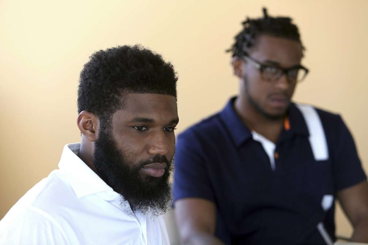Rashon Nelson, listens to a reporter's question alongside Donte Robinson during an interview with the Associated Press Wednesday April 18, 2018 in Philadelphia. Their arrests at a local Starbucks quickly became a viral video and galvanized people around the country who saw the incident as modern-day racism. In the week since, Nelson and Robinson have met with Starbucks CEO Kevin Johnson and are pushing for lasting changes to ensure that what happened to them doesn't happen to future patrons. They are also still processing what it means to have had an everyday encounter escalate into a police confrontation. (AP Photo/Jacqueline Larma)