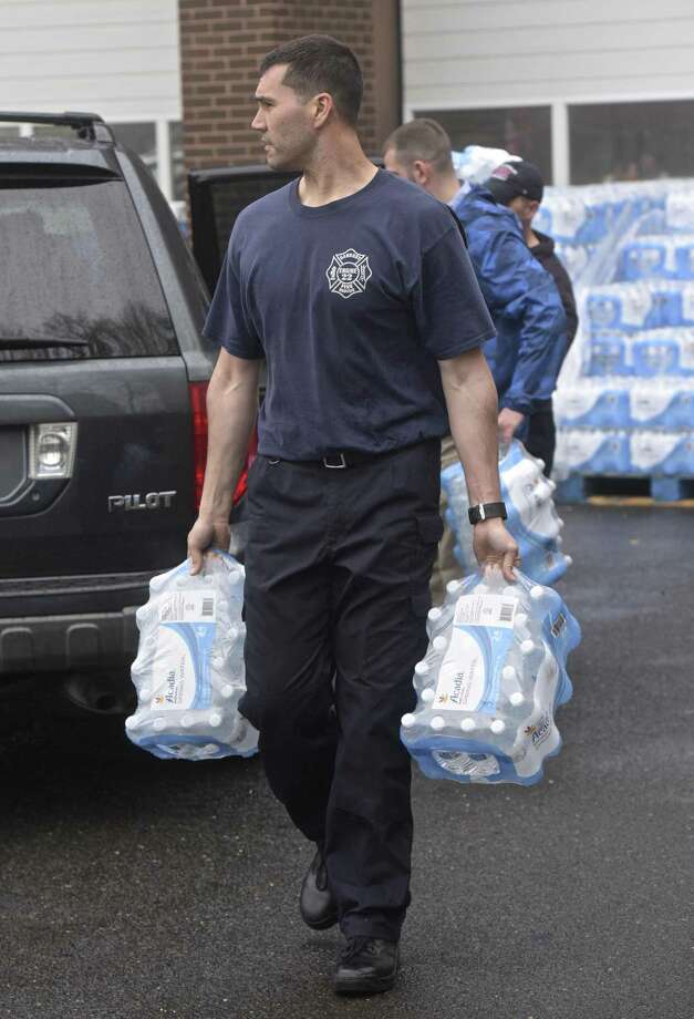 Danbury fire fighter Chris Moore carries cases of bottled water to a waiting car as the City of Danbury distributes donated bottled water at the Fire Department head quarters on New Street Wednesday afternoon. Residents have been asked not to drink city water without boiling it because of a water main break on Monday. April 25, 2018, in Danbury, Conn. Photo: H John Voorhees III / Hearst Connecticut Media / The News-Times
