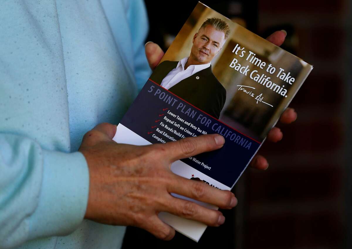 A registered voter clutches campaign literature after a visit from volunteers canvassing a neighborhood for Republican gubernatorial candidate Travis Allen in Concord, Calif. on Saturday, April 21, 2018.