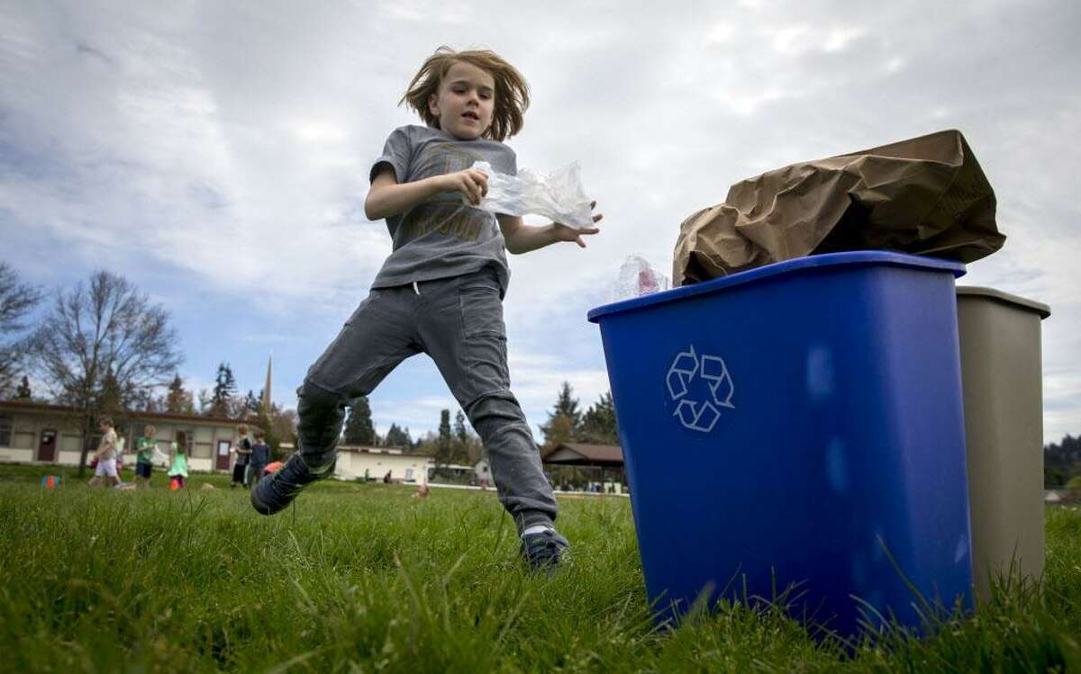 A first grader races to the recycling bin during a race to help students understand recycling practices during Earth Day activities.
