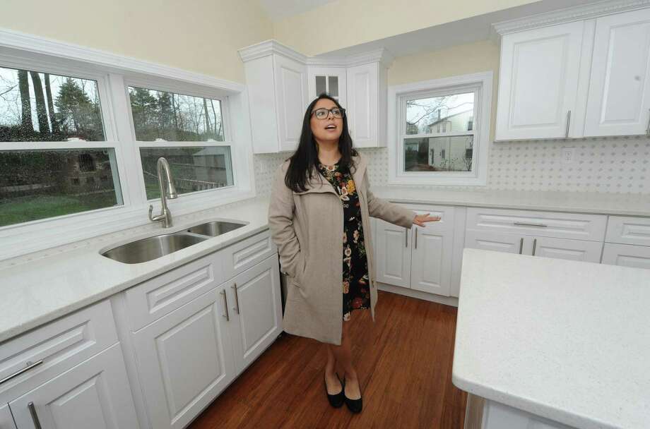 Gabby Villacis with Modern Day Real Estate shows the home at 4 Chelene Road for sale at $469,000 Wednesday, April 25, 2018, in Norwalk, Conn. The newly renovated cape has all new mechanicals, new kitchen and baths and has a square footage of 1700 feet. Photo: Erik Trautmann / Hearst Connecticut Media / Norwalk Hour