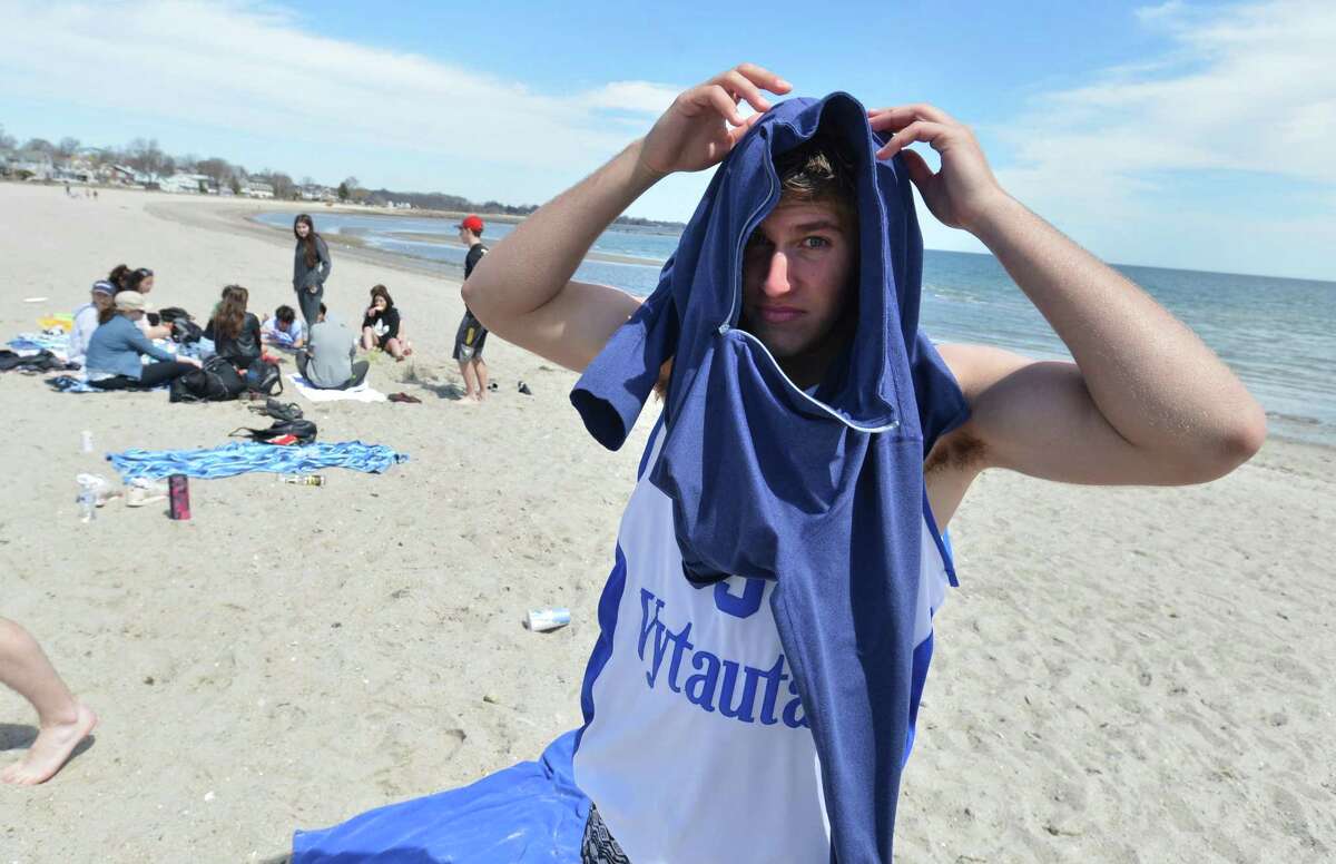 Charles Sagdiyev pulls on a hoodie after taking a swim with classmates from Wooster School in Danbury during a warm day at Compo Beach on Tuesday. The students were there for senior skip day.