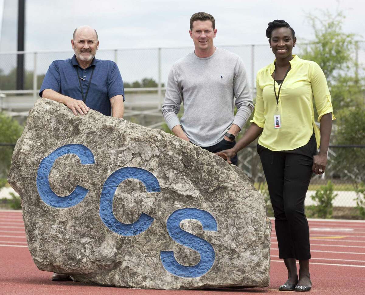 Cornerstone Christian School's new athletic hires Johnny Booty, left, football coach Abram Booty, center and girls basketball coach Sophia Young-Malcolm pose Wednesday, April 25, 2018 with the CCS rock moved from the school previous facility to the current location on NW Military Drive outside Loop 1604.