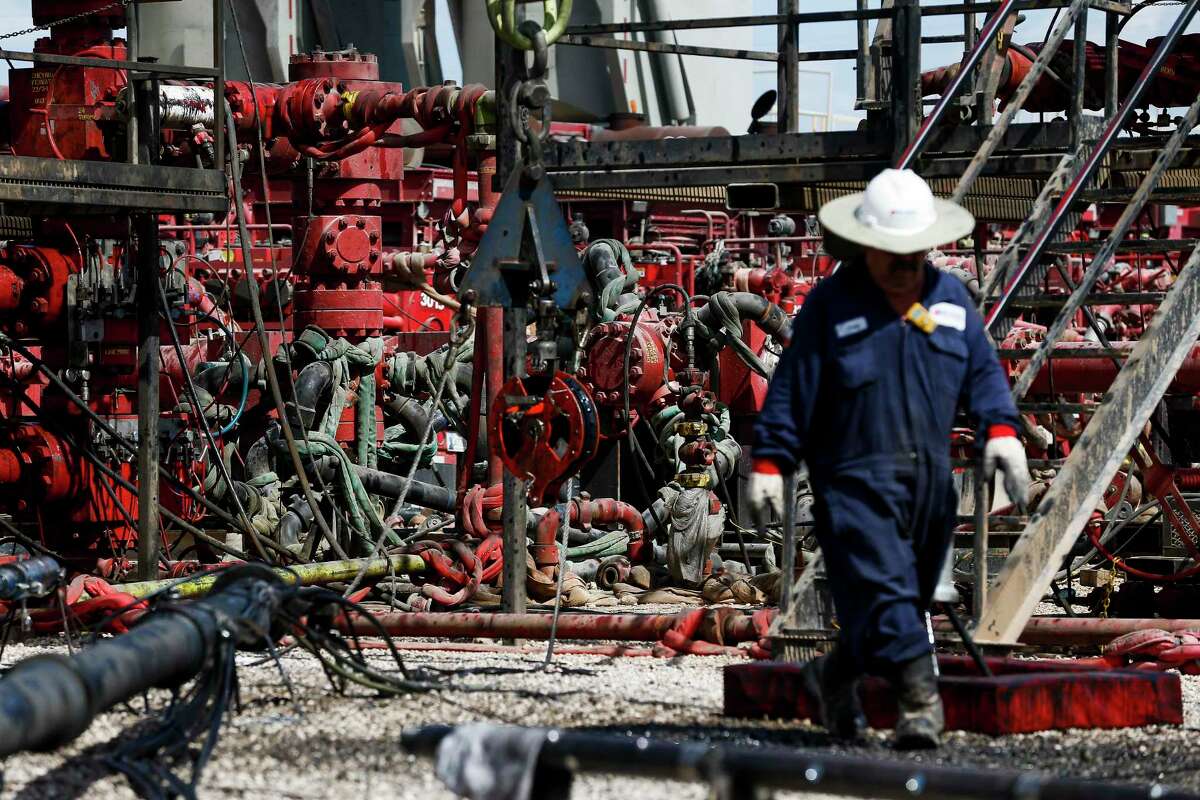 An employee walks by pressure pumps before hydraulic fracturing operations begin at a Chevron drilling in the Permian Basin.