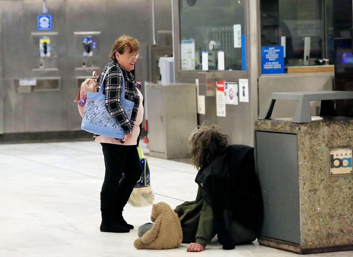 Kathleen Dumag (l to r) , of Brentwood, stops to talk with Casey Watson, who is homeless, as he sits on the ground at the Civic Center / UN Plaza Station on Friday, April 27, 2018 in San Francisco, Calif.
