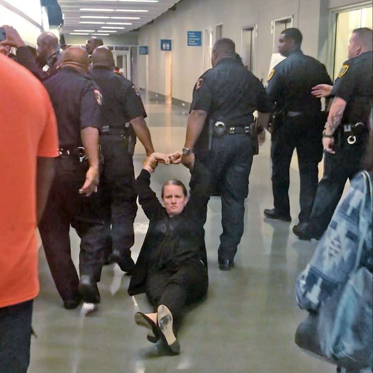 In this April file photo, law enforcement officers drag Jenny Espeseth out of Houston ISD's board room and down a hallway. Espeseth, who has two children enrolled in HISD schools, refused to leave the board room after HISD Board President Rhonda Skillern-Jones ordered it be cleared during a special school board meeting. While Espeseth was released minutes later, two other women at the meeting were transported to the Harris County Jail before their misdemeanor charges were dropped on Wednesday. This is a still image taken from video.