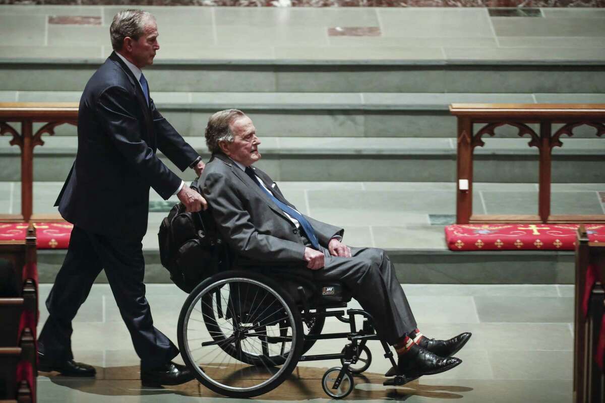 Former president George W. Bush, left, wheels his father, former president George H.W. Bush into the church for the funeral for first lady Barbara Bush at St. Martin's Episcopal Church on Saturday, April 21, 2018, in Houston. The elder Bush is hospitalized, recovering from an infection that spread to his blood.