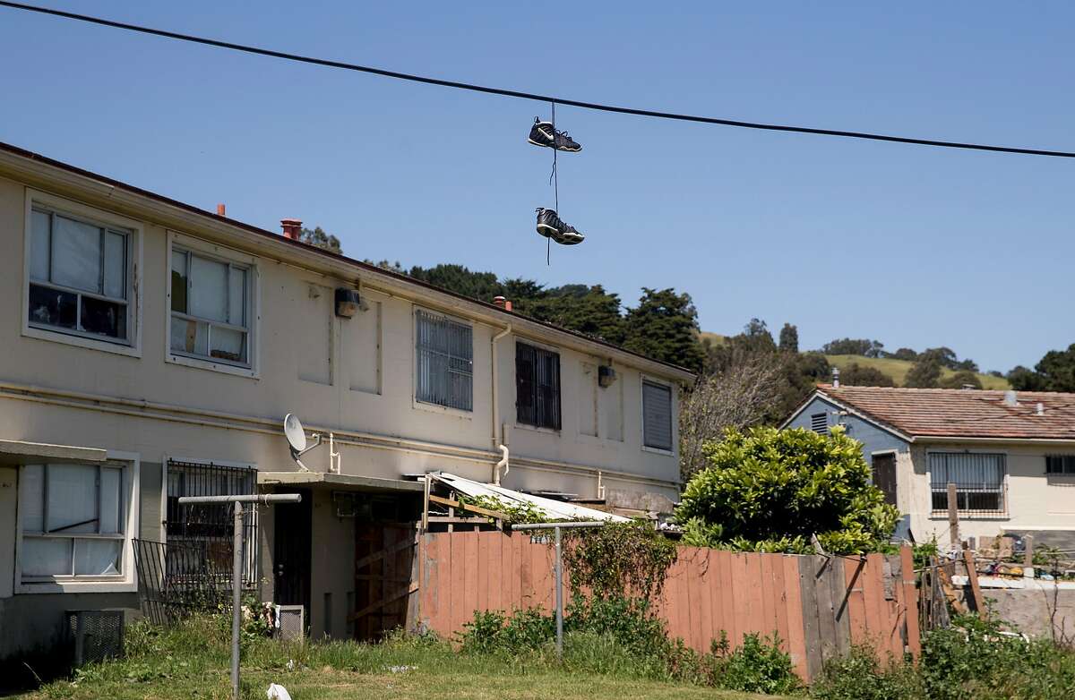 A pair of sneakers hangs on a power line above a row of public housing units Wednesday, April 25, 2018 in the Sunnydale neighborhood of San Francisco, Calif.