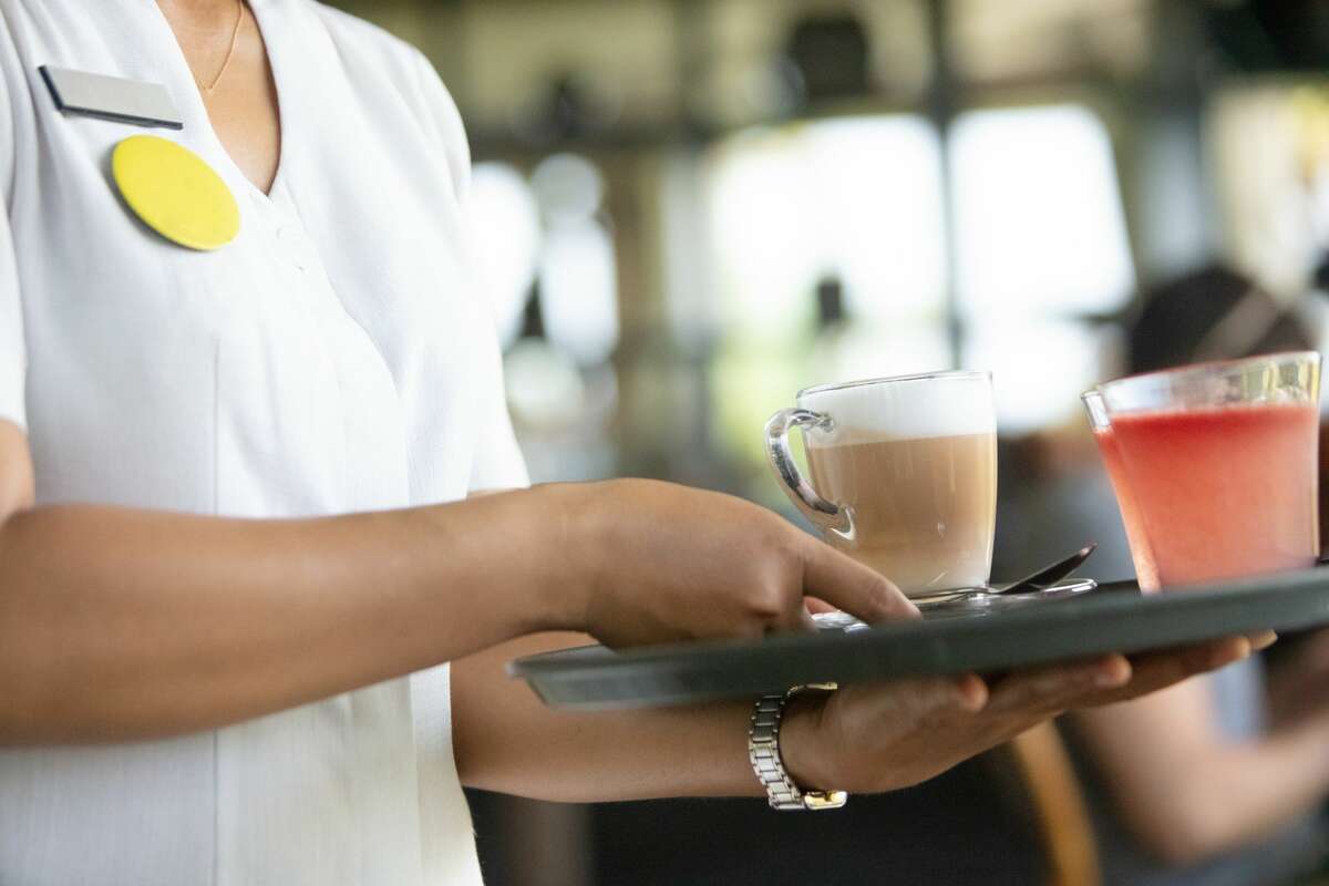 A waitress serving juice and coffee.  