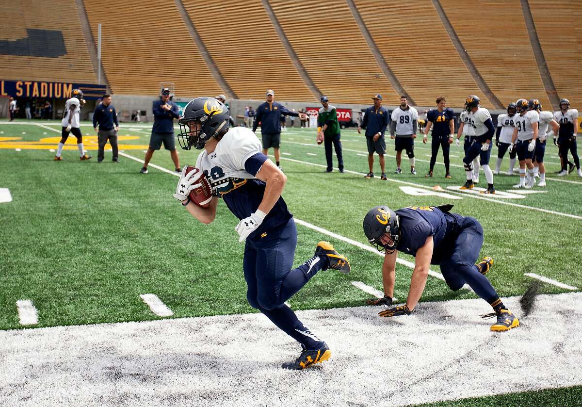 California running back Biaggio Ali Walsh, left, escapes a tackle by defensive back Daniel Elter during the spring football scrimmage at Memorial Stadium, Saturday, April 28, 2018 in Berkeley, Calif.