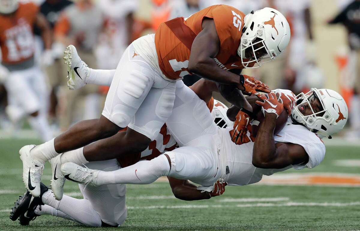 Texas wide receiver Devin Duvernay, right, is hit by defensive back Donovan Duvernay after making a catch for a first down during the team's Orange-White intrasquad spring college football game, Saturday, April 21, 2018, in Austin, Texas. (AP Photo/Eric Gay)