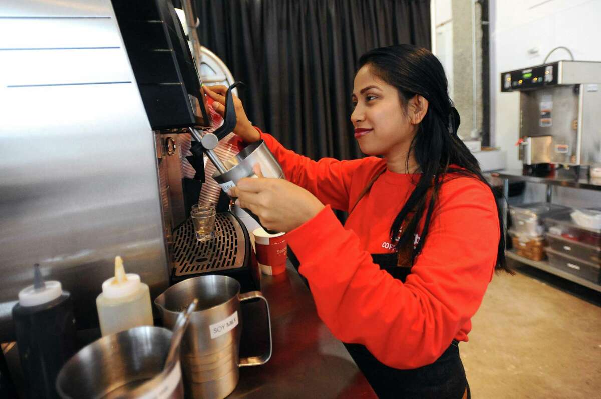 Barista Ferdous Ara makes a latte inside the new coffee shop Coffee Spot, at 24 Harbor Point Road, in Stamford, Conn., on Wednesday, April 25, 2018.